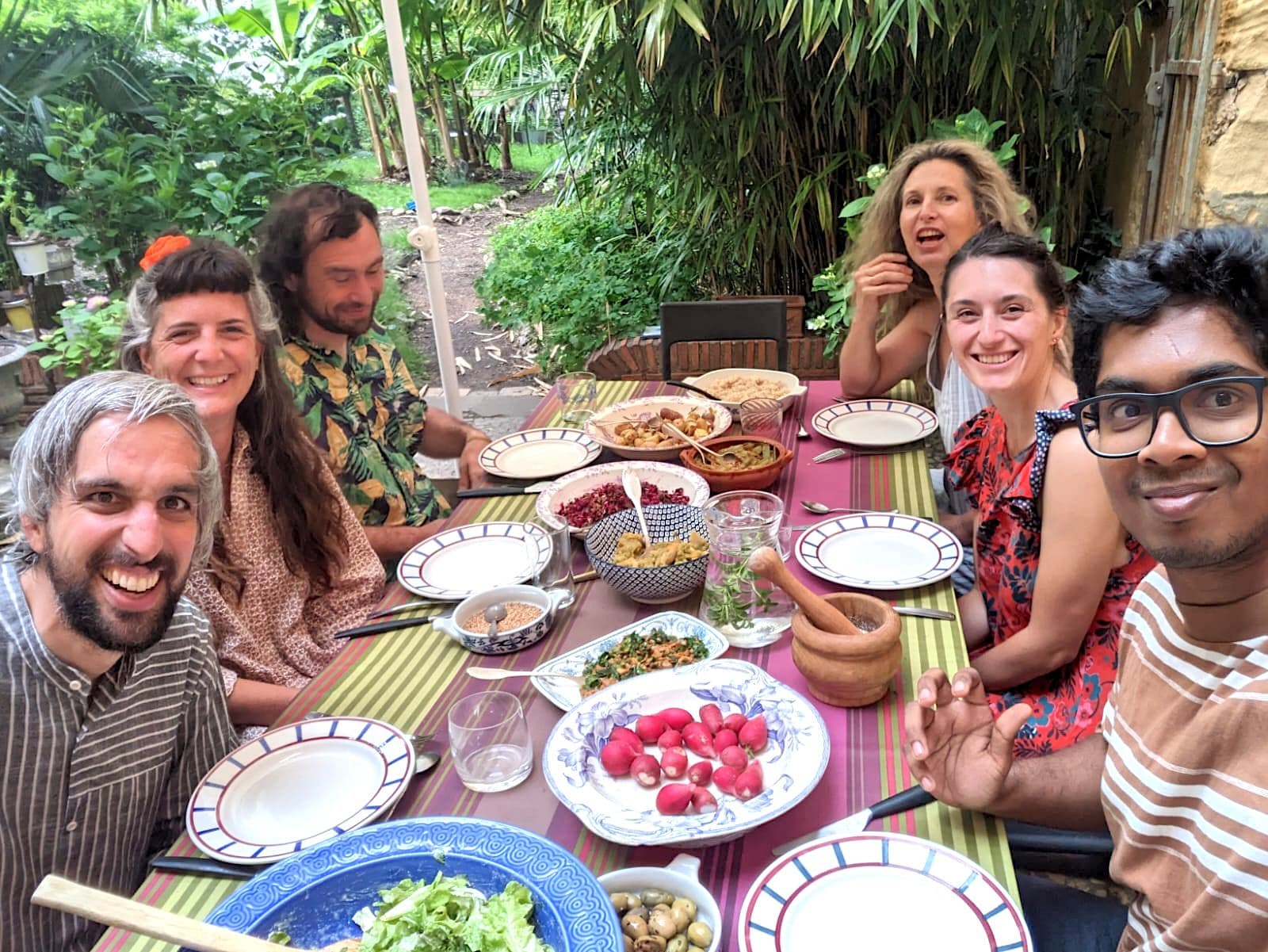 Friends laughing around a long table in a garden